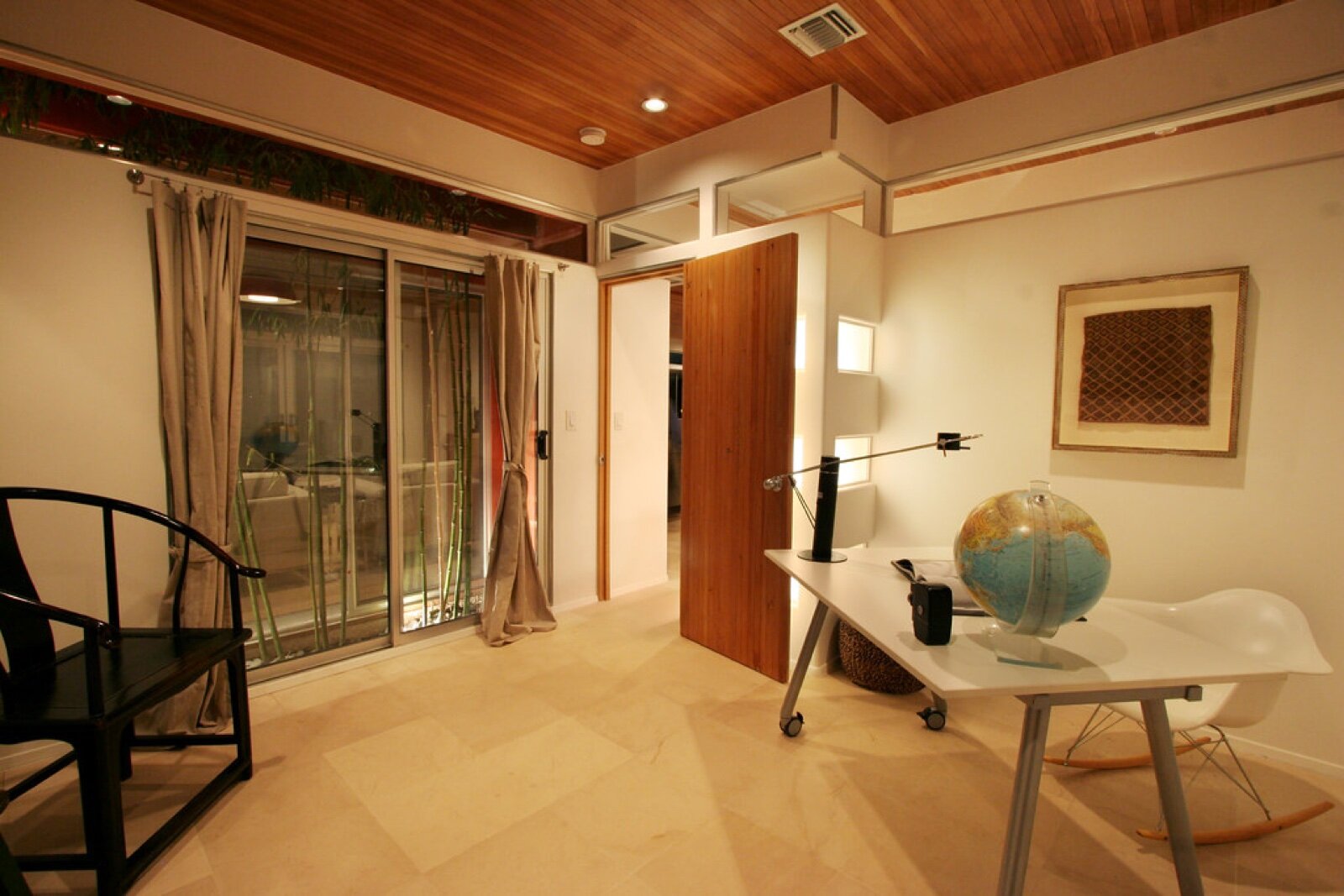 A home office room with sliding doors, a desk and tiled floor