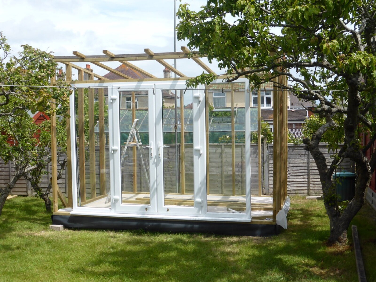 A timber-framed garden building under construction in a UK back garden