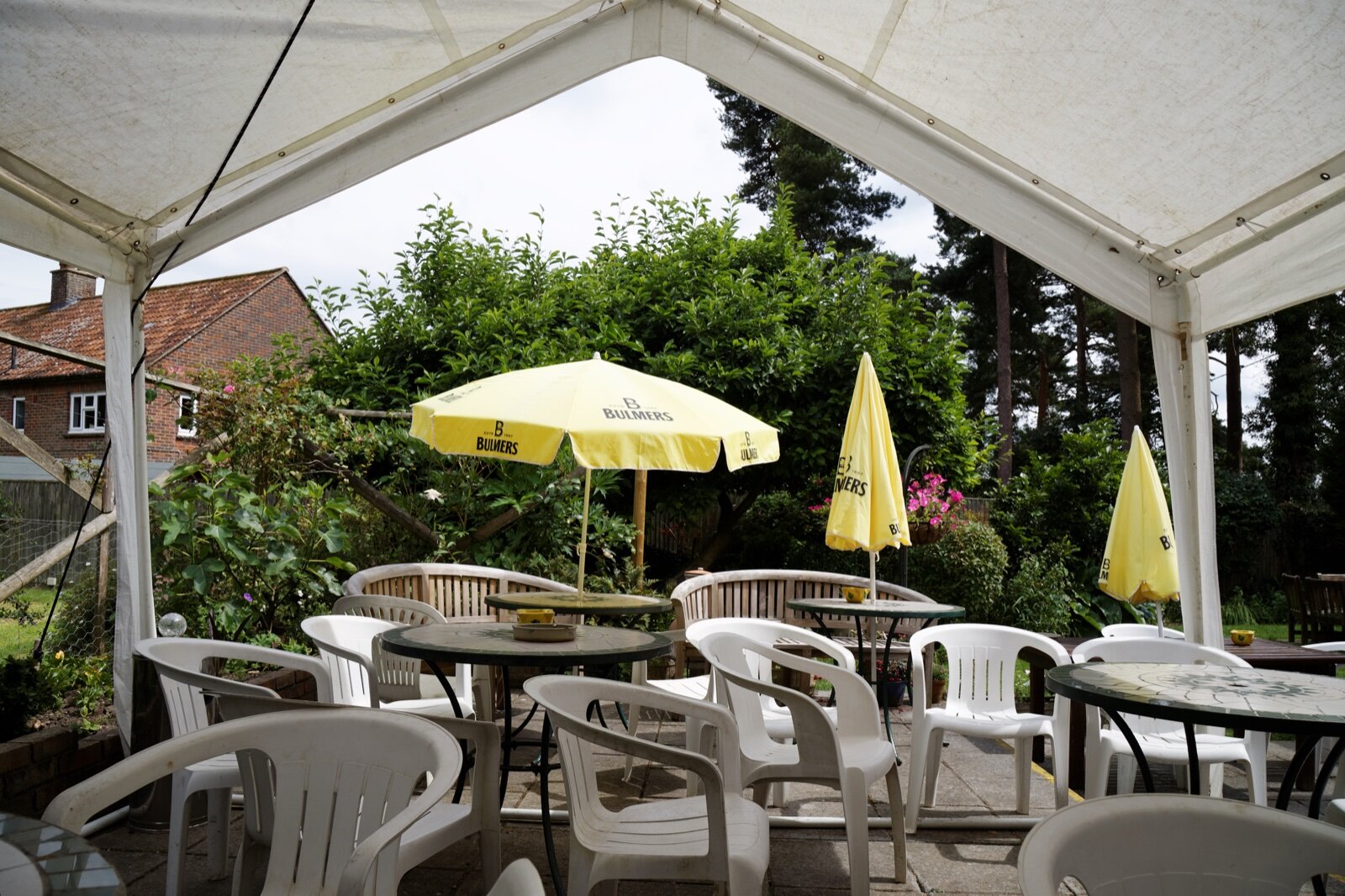 Large white fabric-canopy gazebo covering tables and chairs in a pub garden