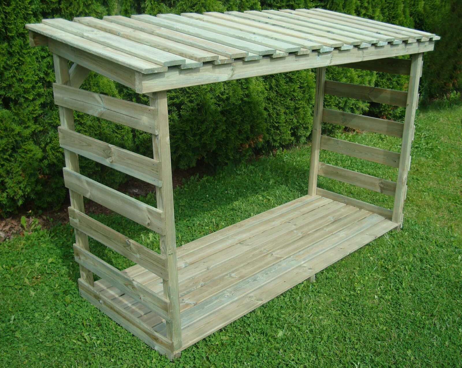 Empty timber log store on a lawn with slatted sides, a slatted roof and a floor raised off the ground