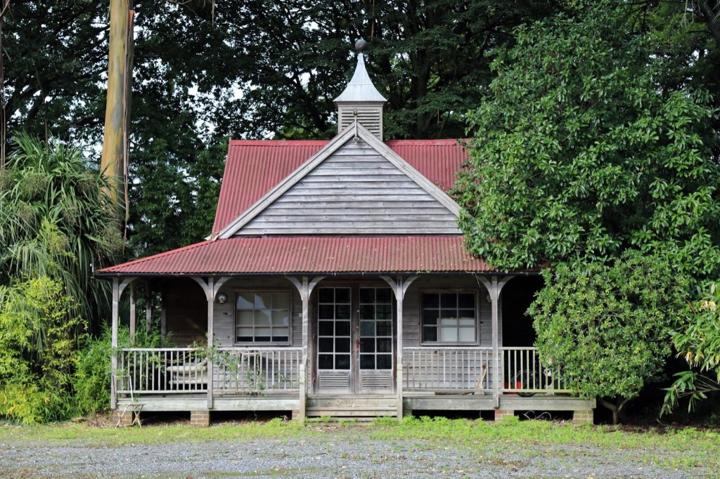 Timber summer house with fully glazed double doors flanked by multi-pane windows and a covered veranda