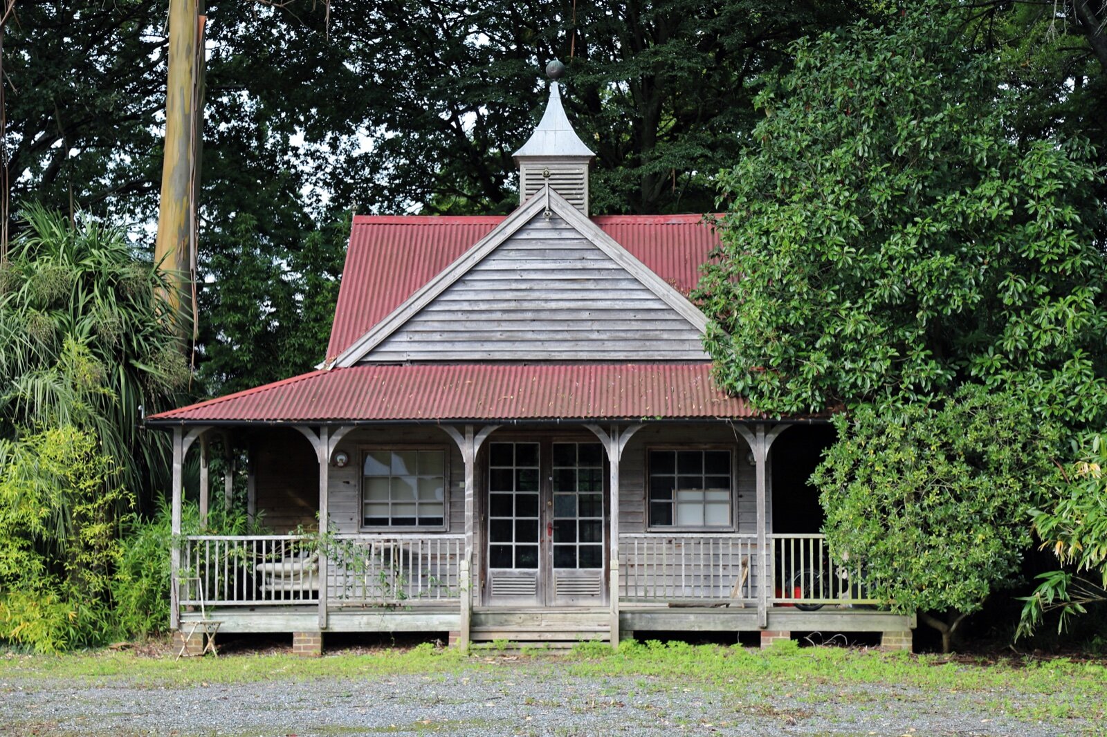 Timber summer house with fully glazed double doors flanked by multi-pane windows and a covered veranda