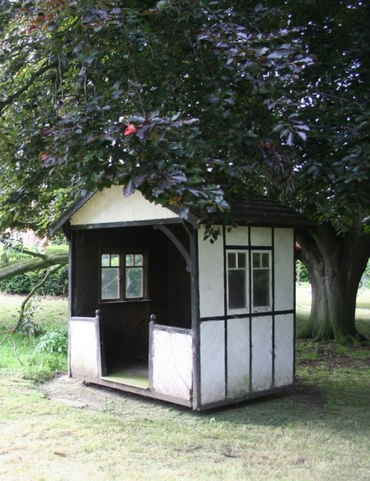 Small timber summerhouse with small-pane windows on two elevations, mounted on a turntable