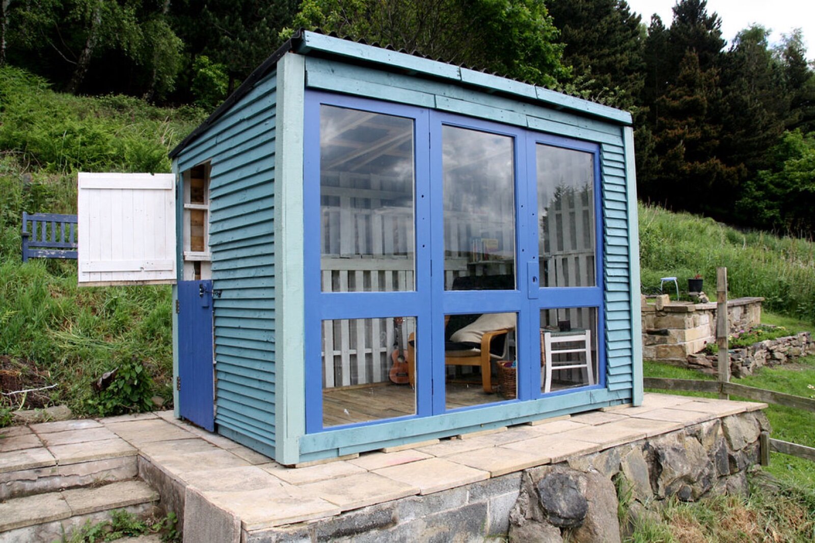 Timber summer house with glazed doors on a paved deck in a garden