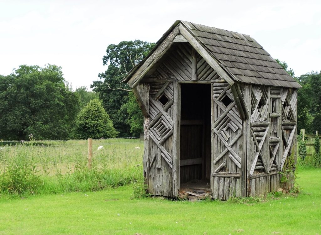 Small rustic timber summer house with a shingle roof on a lawn