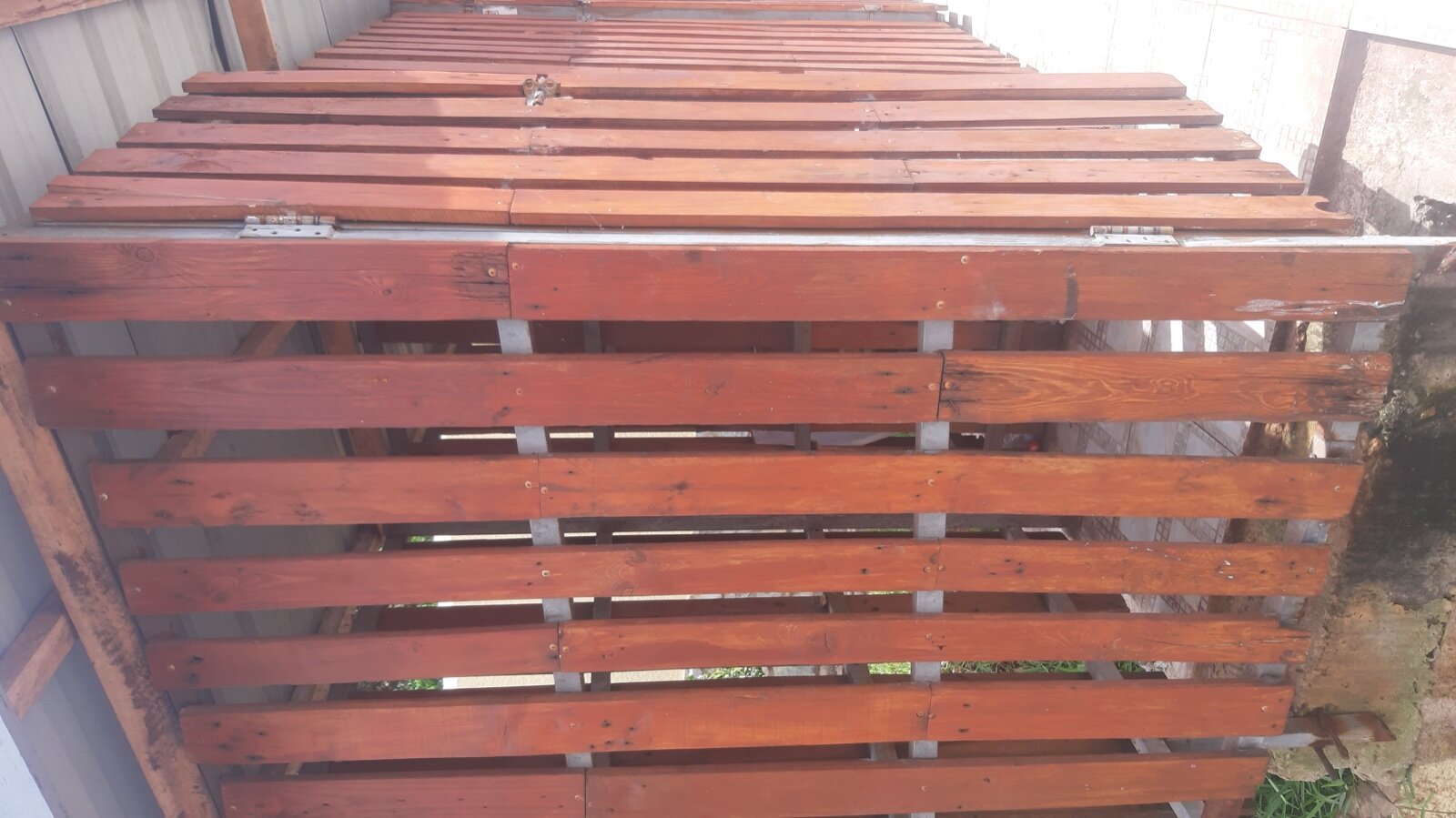 Slatted timber bin shed with a hinged door and corrugated roof