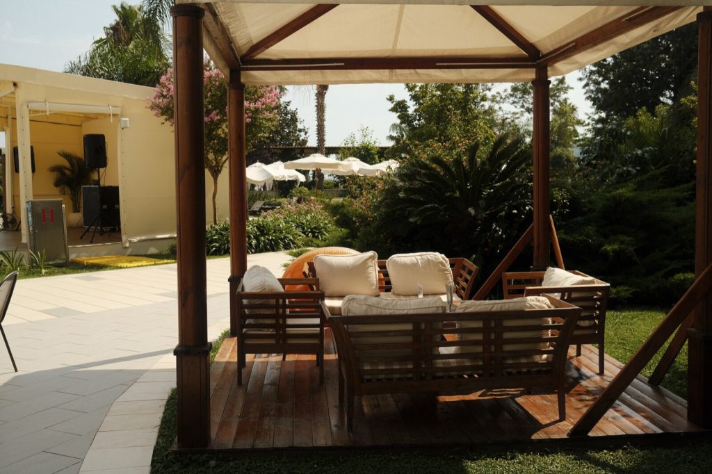 Timber garden sofa and armchairs with cream cushions under a canopy on decking