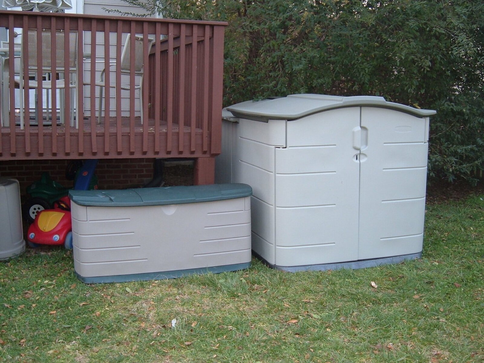 A plastic deck storage box and small storage shed beside a garden deck
