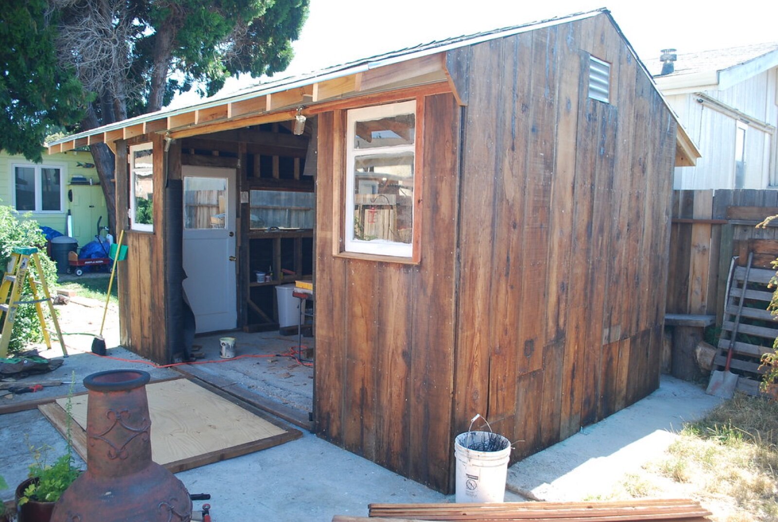 A self-built timber garden shed nearly finished, with the roof rafters still exposed