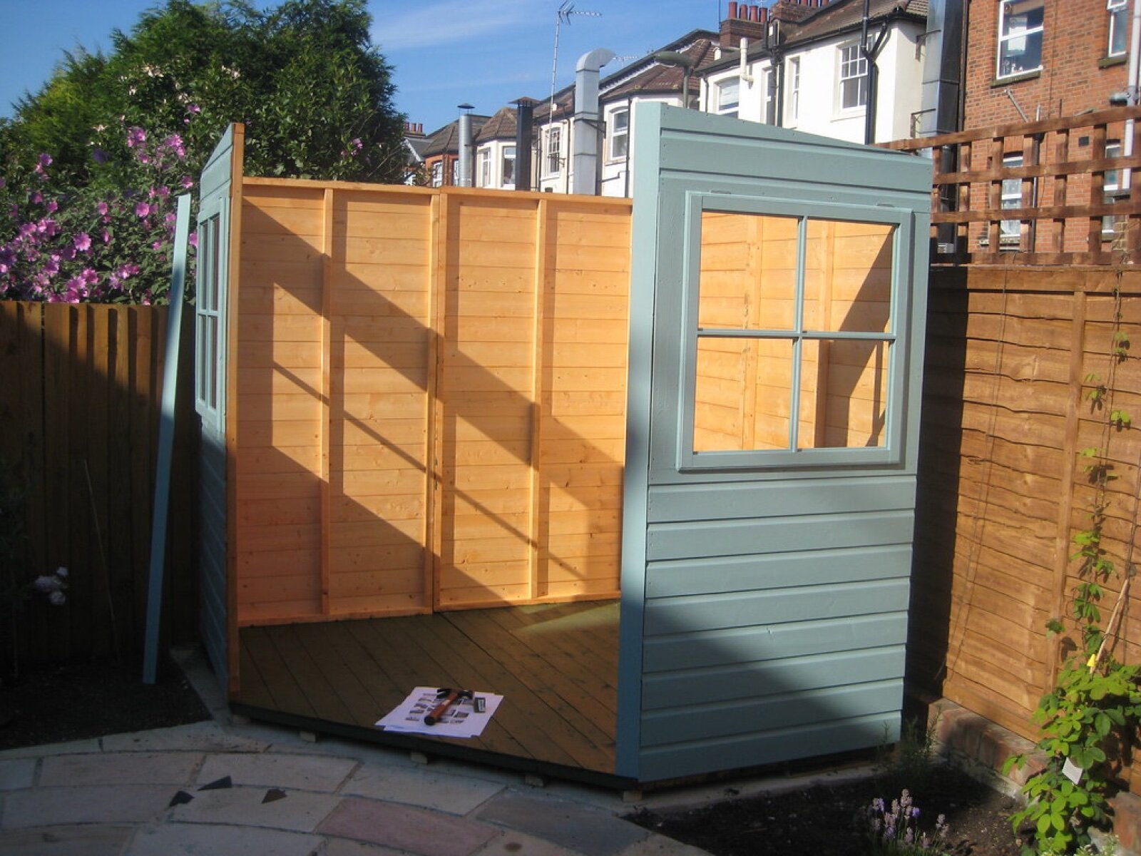 Clad timber wall panels being assembled on a shed floor, with the vertical studs visible on the inside face
